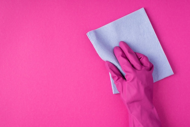 Top view photo of hand in pink glove using pastel blue viscose rag on isolated pink background with blank space