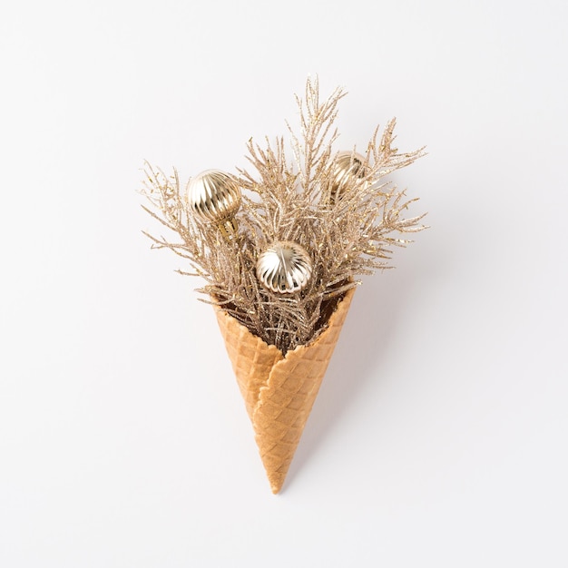 Top view photo of ice cream cone with pine branches and silver christmas tree balls on isolated white background