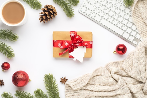 Top view photo of keyboard cup of hot drinking red christmas tree balls pine twigs cone anise cozy sweater and giftbox with fir shaped tag on isolated white background