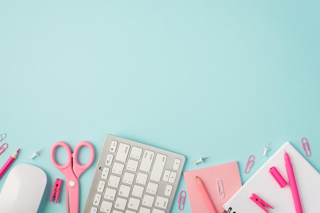 Top view photo of pink stationery pen pencils scissors pins clips sticker organizer keyboard and mouse on isolated pastel blue background with copyspace