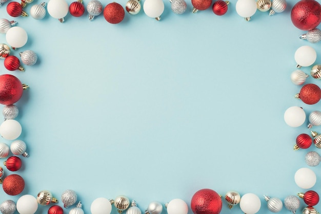 Top view photo of red silver and white christmas tree balls on isolated pastel blue background with copyspace in the middle