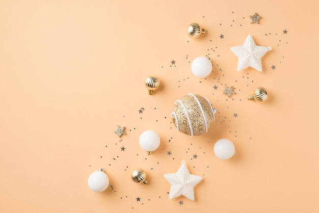 Top view photo of row composition white and golden christmas tree decorations balls shiny stars and sequins on isolated beige background with copyspace