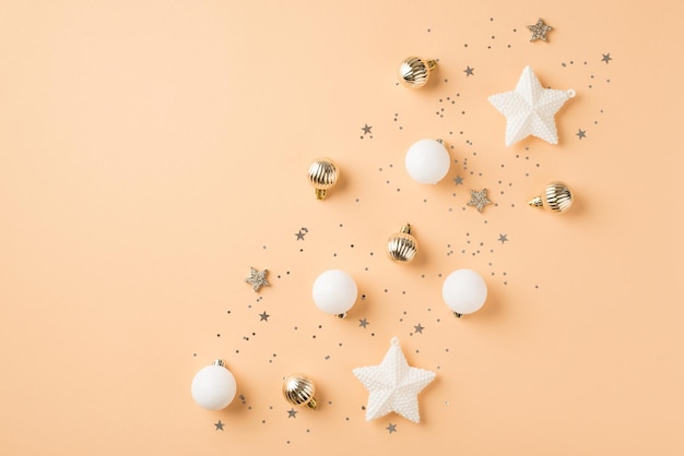 Top view photo of row composition white and golden christmas tree decorations small balls shiny stars and confetti on isolated beige background with blank space