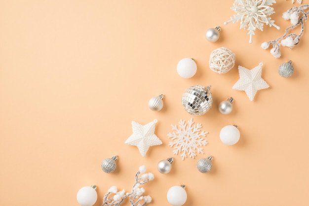 Top view photo of row composition white and silver christmas tree decorations snowflakes disco balls stars and snowy sprigs on isolated beige background with empty space