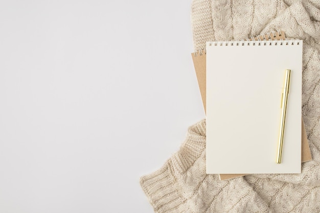 Top view photo of two organizers pen and knitted pullover on isolated white background with copyspace