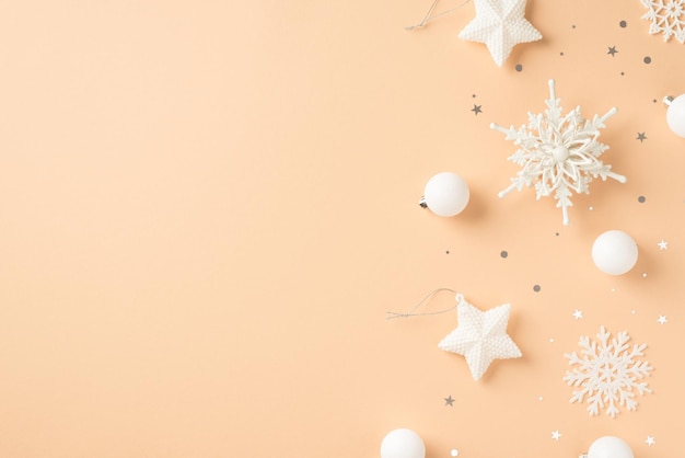 Top view photo of white christmas tree decorations snowflakes stars balls and confetti on isolated beige background with copyspace