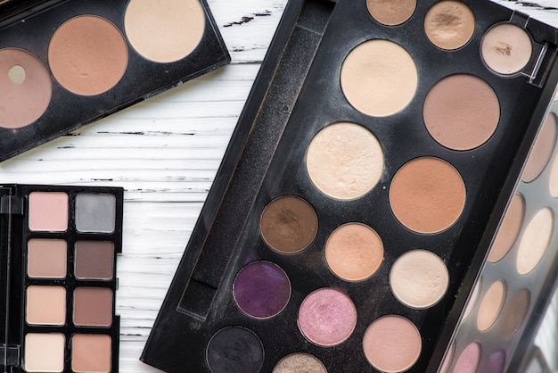 Top view of pink and brown tone make up palette on white wooden background