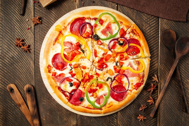 Top view on pizza with salami and bell pepper on the wooden table