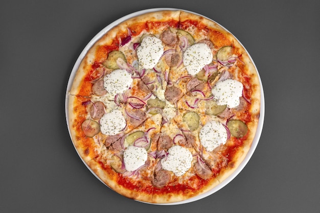 Top view of pizza with sausage, pickled cucumber, onion and horseradish