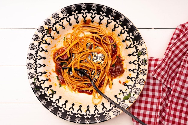 Top view of a plate of Italian spaghetti with sausage and tomato sauce with leftover pasta and sauce