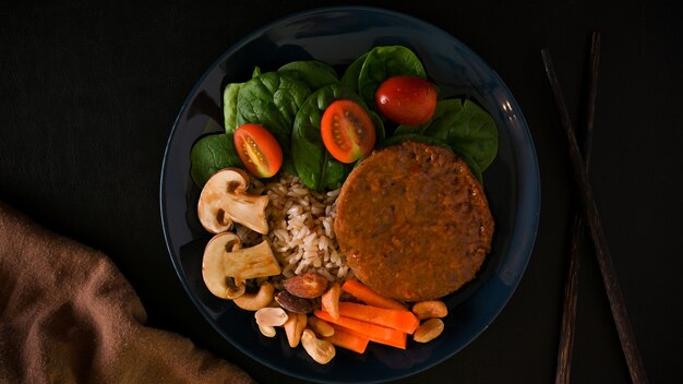 Photo top view of a plate of tasty vegan meal soy protein cutlet burger with brown rice and vegetables