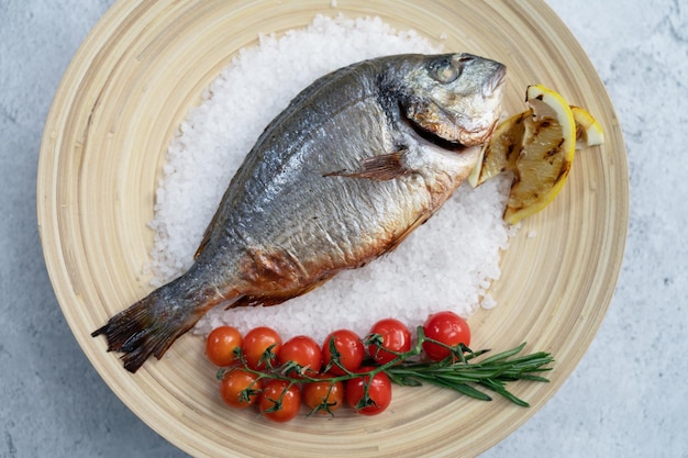 Top view of plate with fresh grilled dorado fish with lemon and tomato