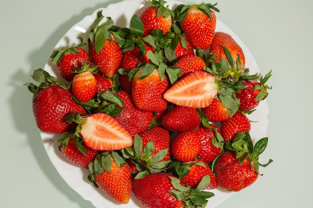 Top view on a plate with ripe strawberry with leaves over a grey background. Space for text