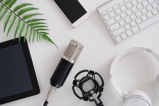 Top view podcast microphone, keyboard, tablet and headphones on white background