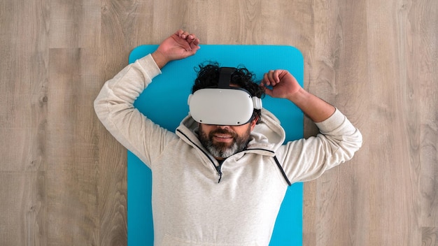 Top view portrait of tired caucasian fitness man resting after make exercise with a vr headset Sportsman enjoying virtual reality glasses to practicing sport and lying on ground at living room house