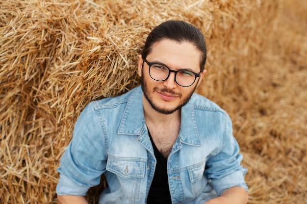 Top view portrait of young smiling man sitting near haystacks.