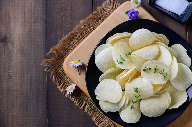 Top view of Potato chips bowl and salt on wood background