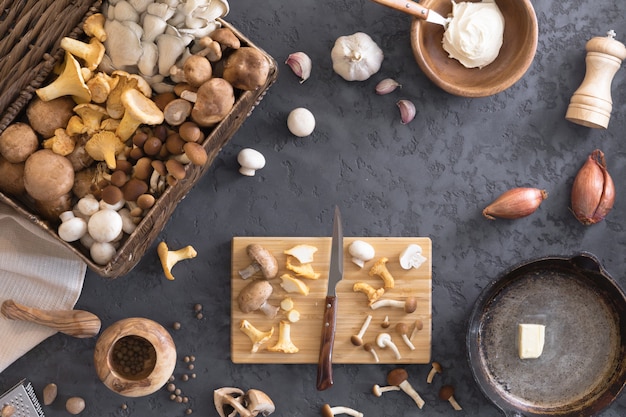 Top view of preparation and frying of edible wild mushrooms, food photo. Mix of chanterelle, portobello, shiitake in Cast-iron pan. Cooking with spices, butter, parsley, onion, leek, garlic.