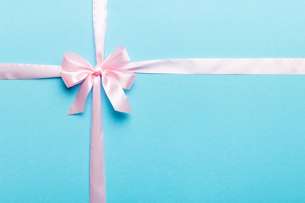 Top view of purple ribbon rolled and pink bow isolated on colored background Flat lay with copy space