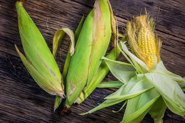 Top view raw corn On old wooden table. Raw corn harvest Ready to cook