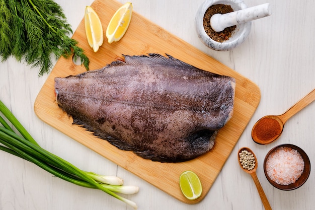 Top view of raw fresh halibut without head on wooden cutting board