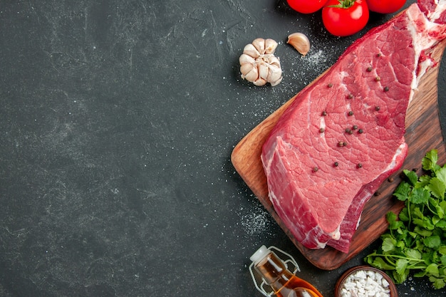 top view raw meat slice with greens and tomatoes