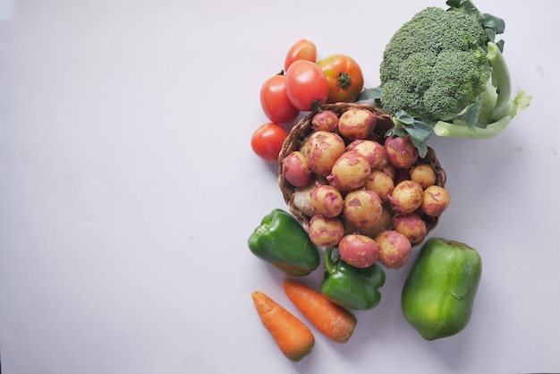 Top view of raw potato in a bowl and vegetables on table