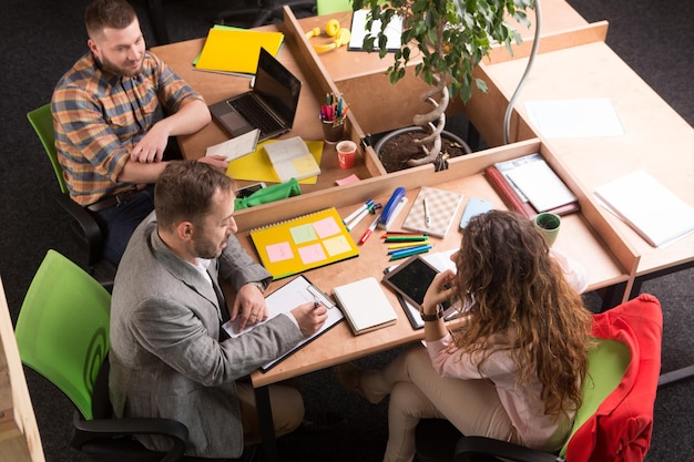 Top view of real business people working in office and discussing different business projects and strategies. Business and freelance concepts.