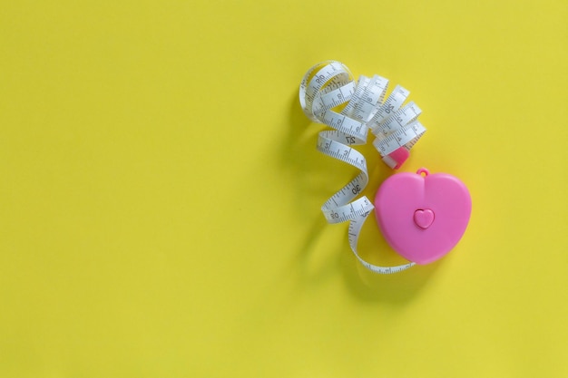 Top view red heart shape and white measurement tape on yellow background For heart check up or chec