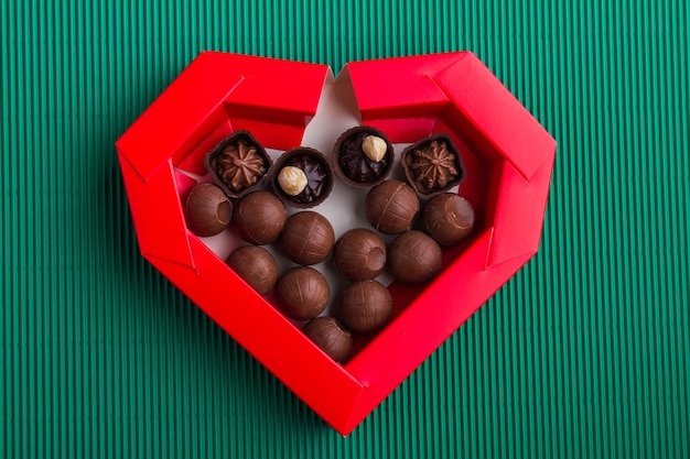 Top view of red heart-shaped box with round chocolate candies. Gift for valentines day.