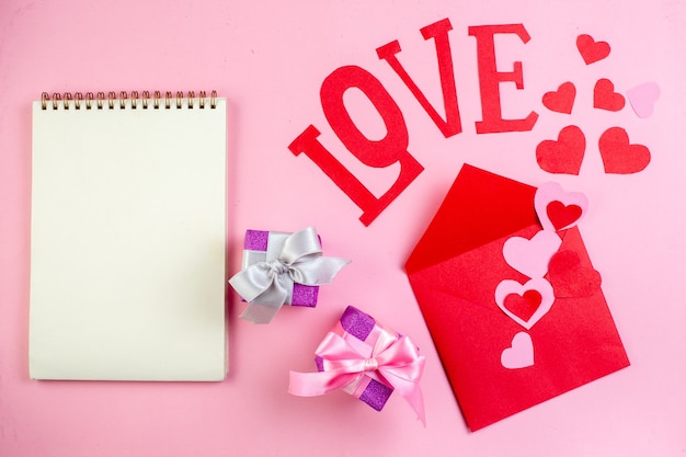 top view red heart stickers love in capital letters envelope notebook gifts on pink background