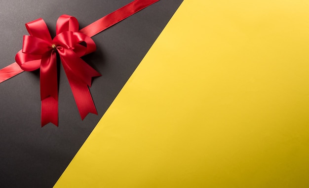 Top view of red ribbon decoration on black and yellow background. Shopping concept boxing day and Black Friday composition.