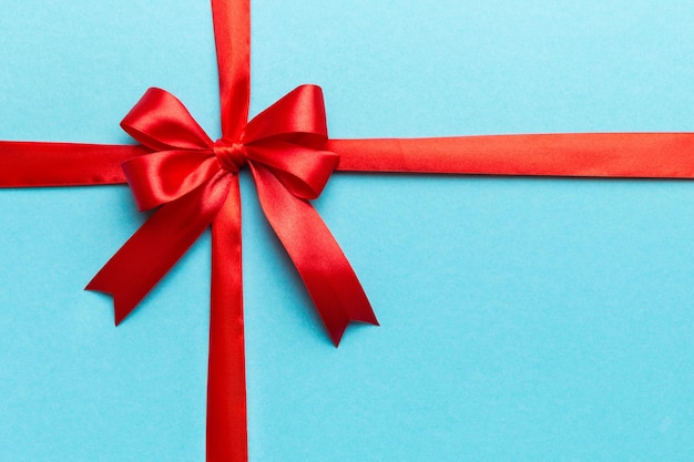 Top view of Red ribbon rolled and red bow isolated on colored background Flat lay with copy space