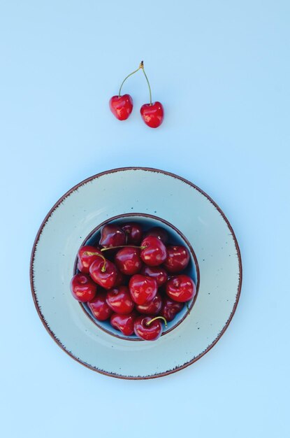 Top view of red sweet cherry on blue plate close up. Vegan, summer food concept. Diet. Healthy life