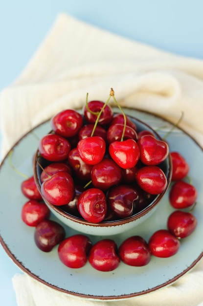 Top view of red sweet cherry on blue plate close up. Vegan, summer food concept. Diet. Healthy life