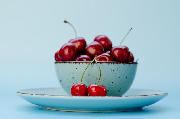 Photo top view of red sweet cherry on blue plate close up. vegan, summer food concept. healthy diet