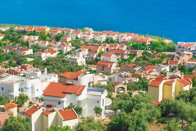 Top view of the resort town with redtiled roofs and white facades near the blue sea