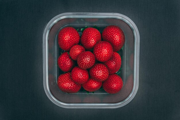 Top view of ripe bright red strawberries in the glass container perfect for grocery usage