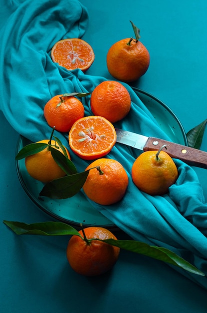 Top view of ripe fresh mandarins or tangerine orangers with green leaves in blue background. Composi