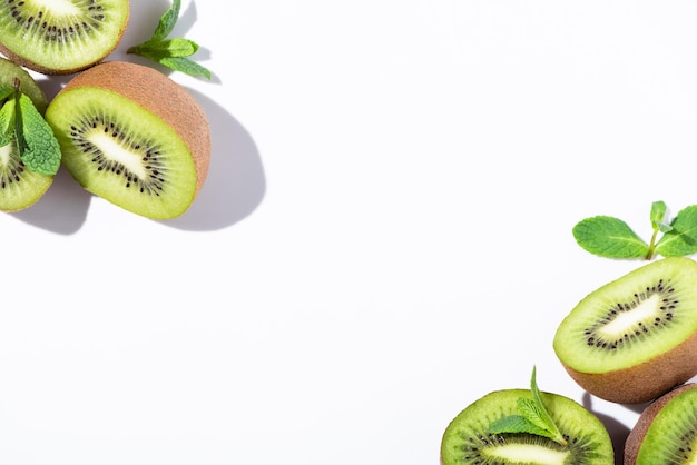 Top view of ripe kiwi fruit halves near green peppermint on white