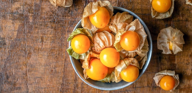 Top view of ripe yellow Cape Gooseberry fruit In a bowl of stainless steel on a wooden background