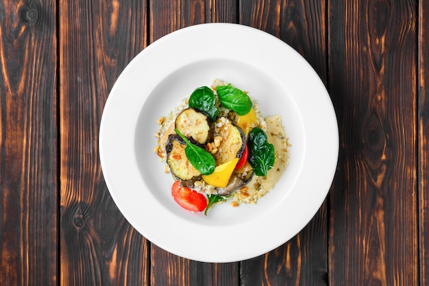 Top view of roasted aubergine with bell pepper, green buckwheat, pine nut and pumpkin seed