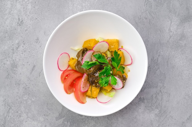 Top view of salad with fried chicken liver, radish, pumpkin, tomato and mustard