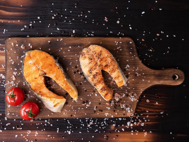 top view of salmon rings arranged on a wooden bottom with tomatoes pressed with salt