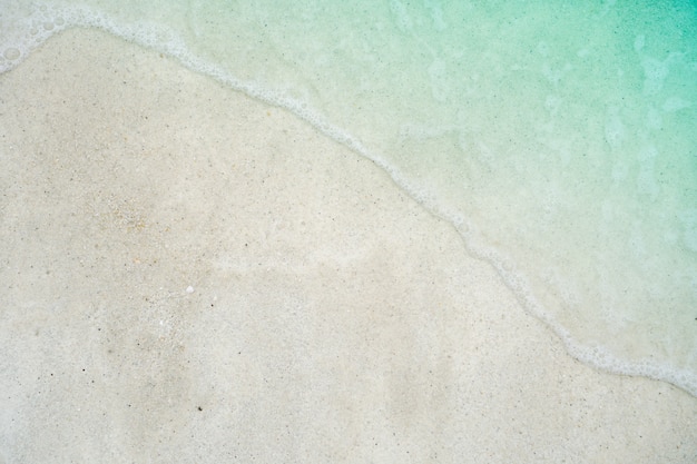 Top view of sand and water clean beach and white sand in summer with sun light blue sky and bokeh background.