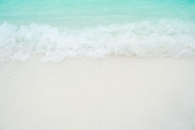 Top view of sand and water clean beach and white sand in summer with sun light blue sky and bokeh background.