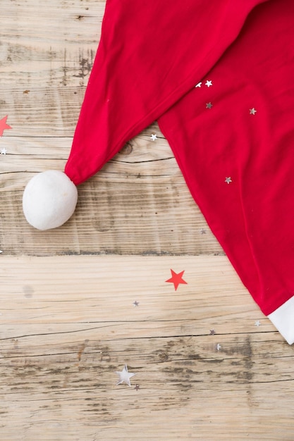 Top view on Santa's hat on retro wooden background with shiny stars. Christmas winter concept