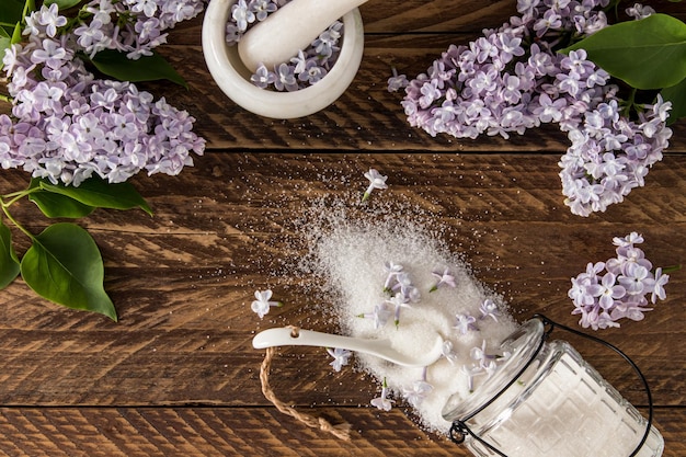 Top view of the scattered sugar of lilac flowers on the wooden table branches lilacs the concept of using sedible plants in cooking