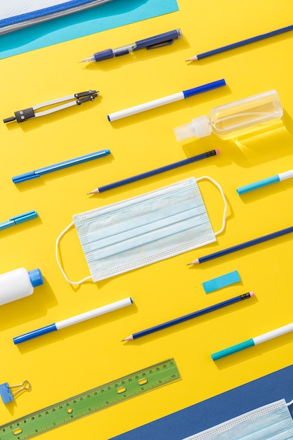 Top view of school supplies with pencils and face mask