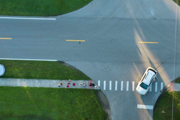 Top view of schoolkids waiting for school bus to arrive in time Kids standing on suburban street sidewalk ready to be picked up in early morning Public transportation in the USA